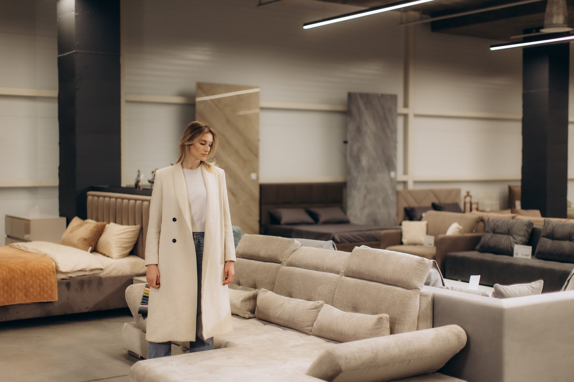 A fashionable woman browses through an upscale furniture store, evaluating stylish sofas and decor.