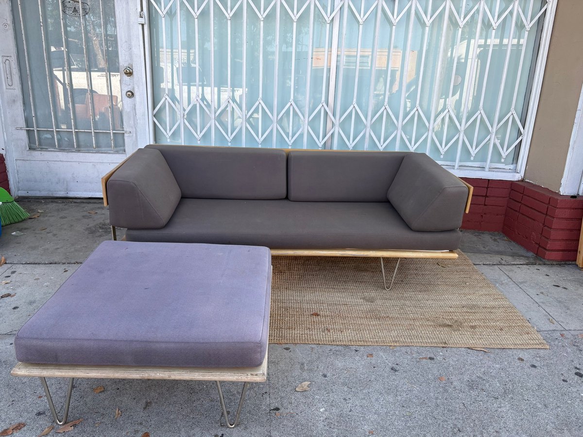 Modern gray sofa and purple ottoman on outdoor concrete patio with metal gate