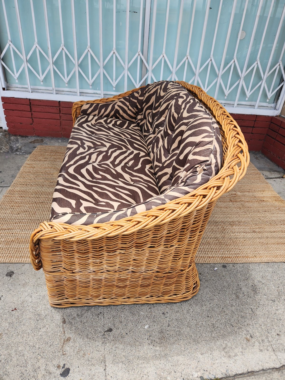 Wicker armchair with zebra-striped brown and white cushioning on a concrete patio