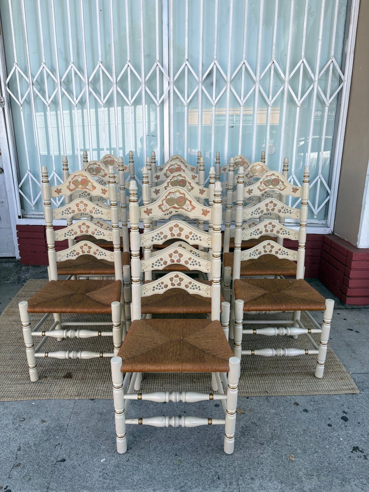 Set of six wooden chairs with woven rush seats arranged around a table against a white pleated curtain backdrop
