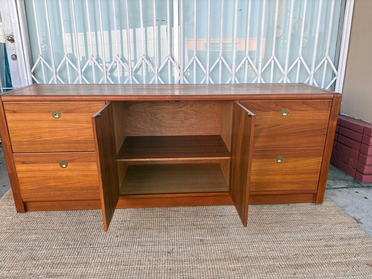 Wooden sideboard with open center cabinet and two side drawers, displayed indoors with white vertical blinds in background