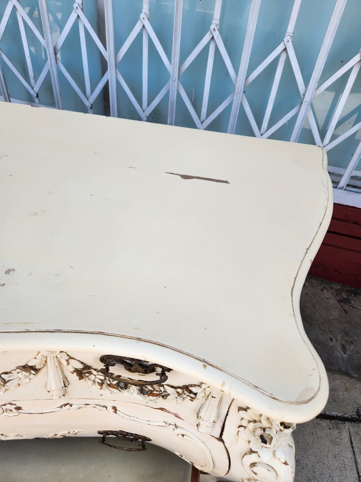 Close-up of weathered white curved wooden furniture piece with peeling paint and visible wear