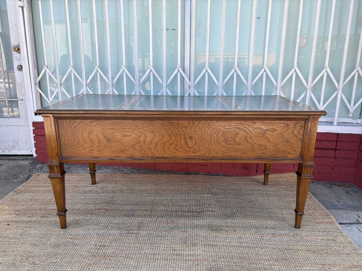 Wooden coffee table with tapered legs on a woven mat against a corrugated metal wall