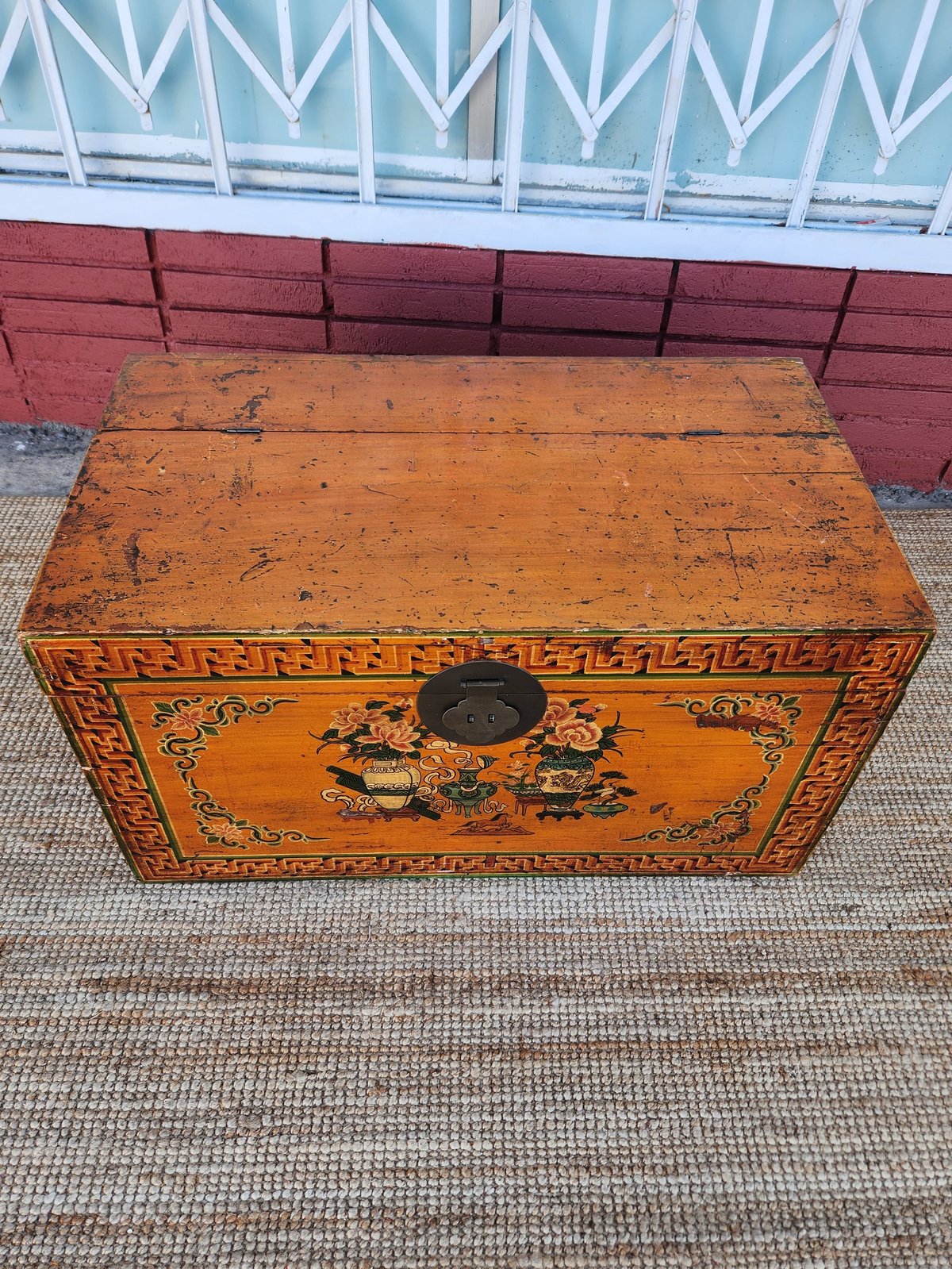 Vintage ornate wooden trunk with gold decorative Asian motifs and black metal hardware on outdoor surface