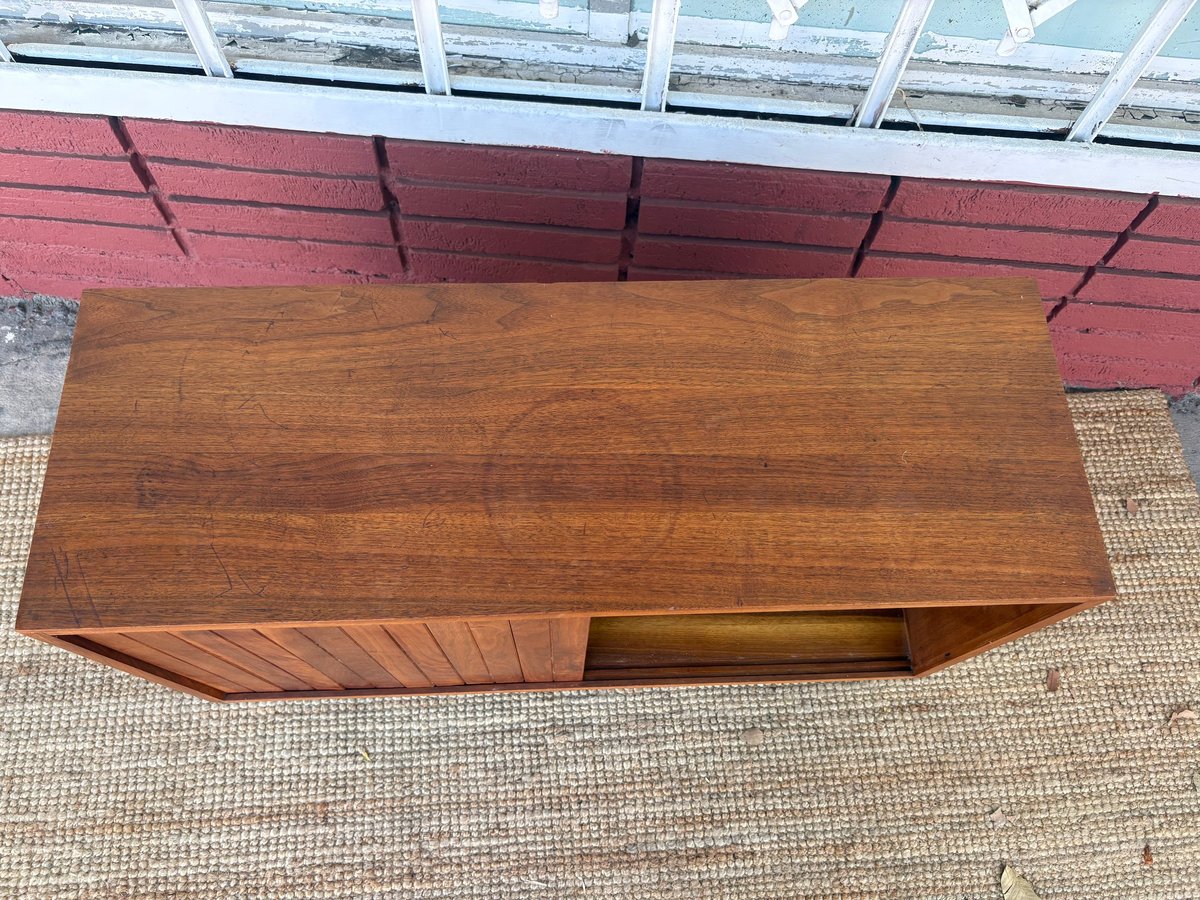 Mid-century modern wooden bench with storage compartment on beige tile floor, skylight visible above