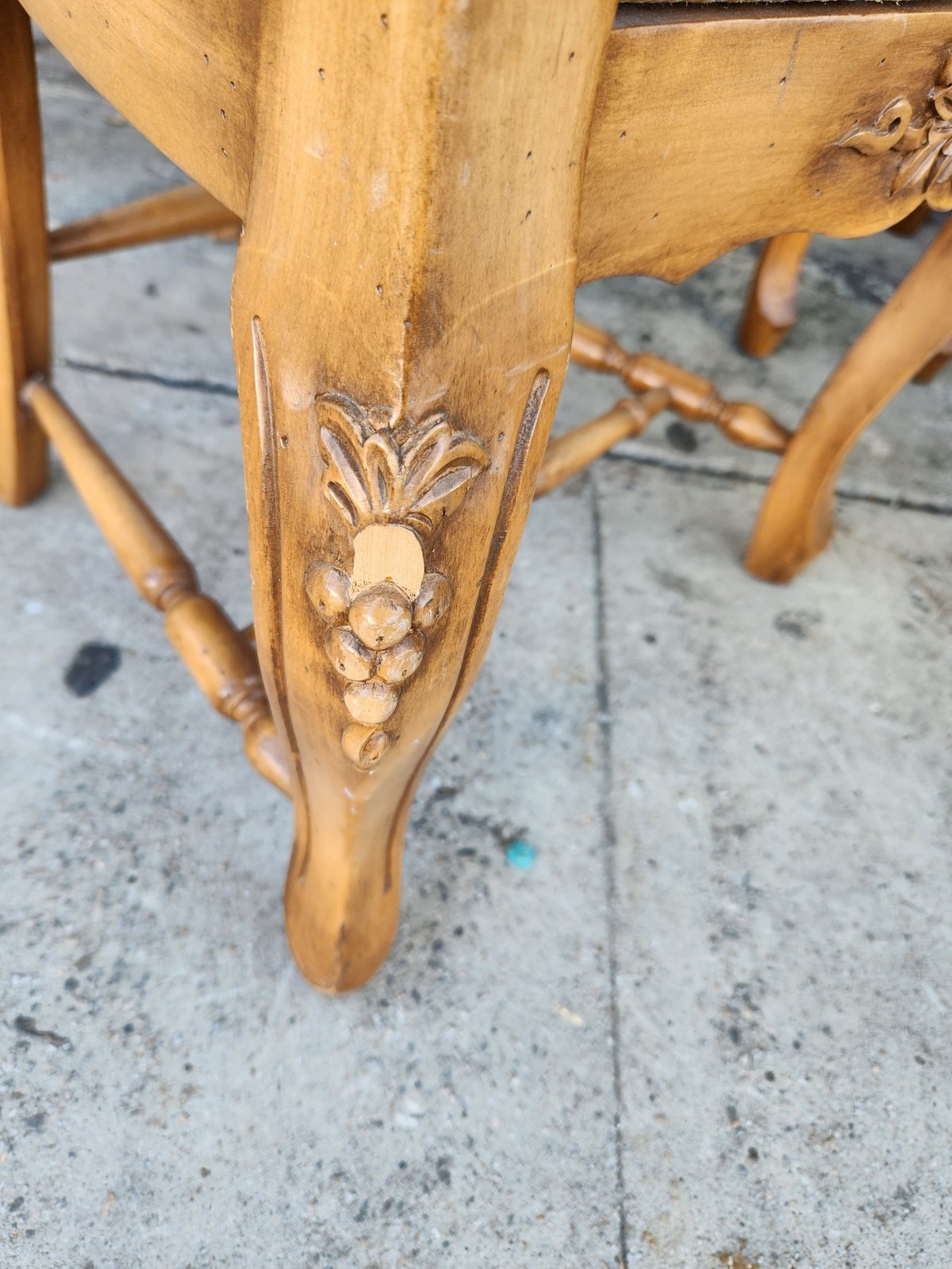 Close-up of wooden furniture leg with carved pineapple and leaf decorative detail