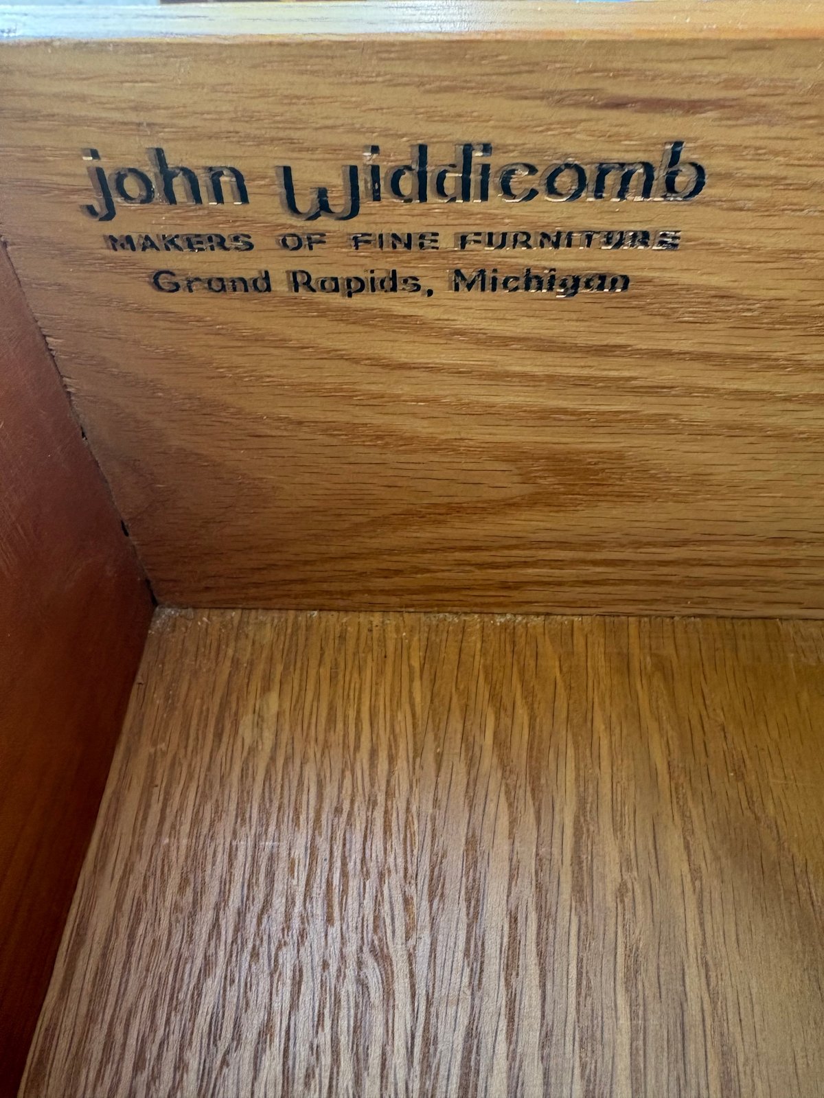 Close-up of wood furniture makers mark reading John Widdicomb, Makers of Fine Furniture, Grand Rapids, Michigan