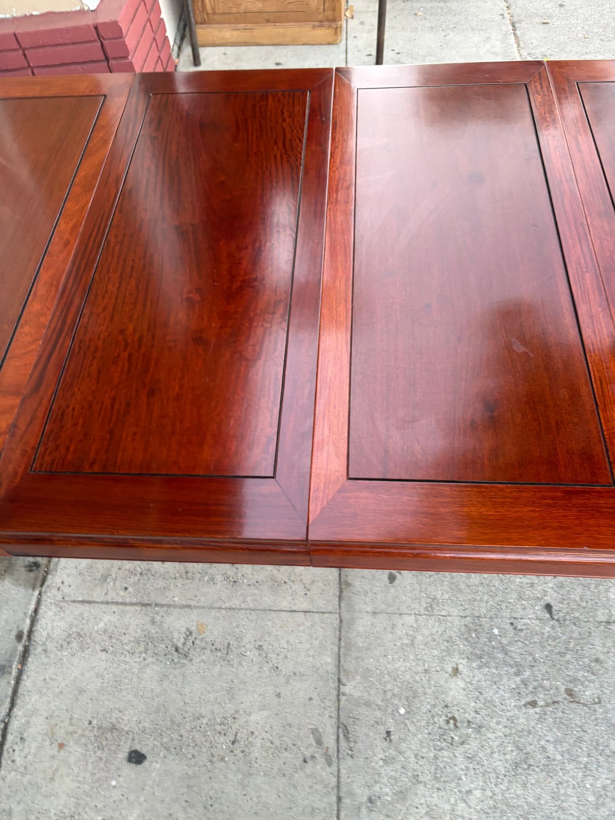 Two wooden cabinet doors with raised panel designs displayed on concrete ground outdoors.