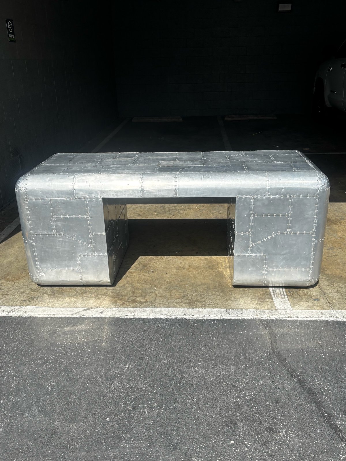 Silver metal airplane-style desk with riveted details and open storage compartment underneath