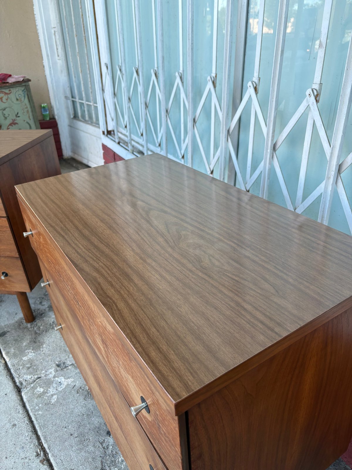 Wooden dresser with light blue accordion-style closet doors in the background