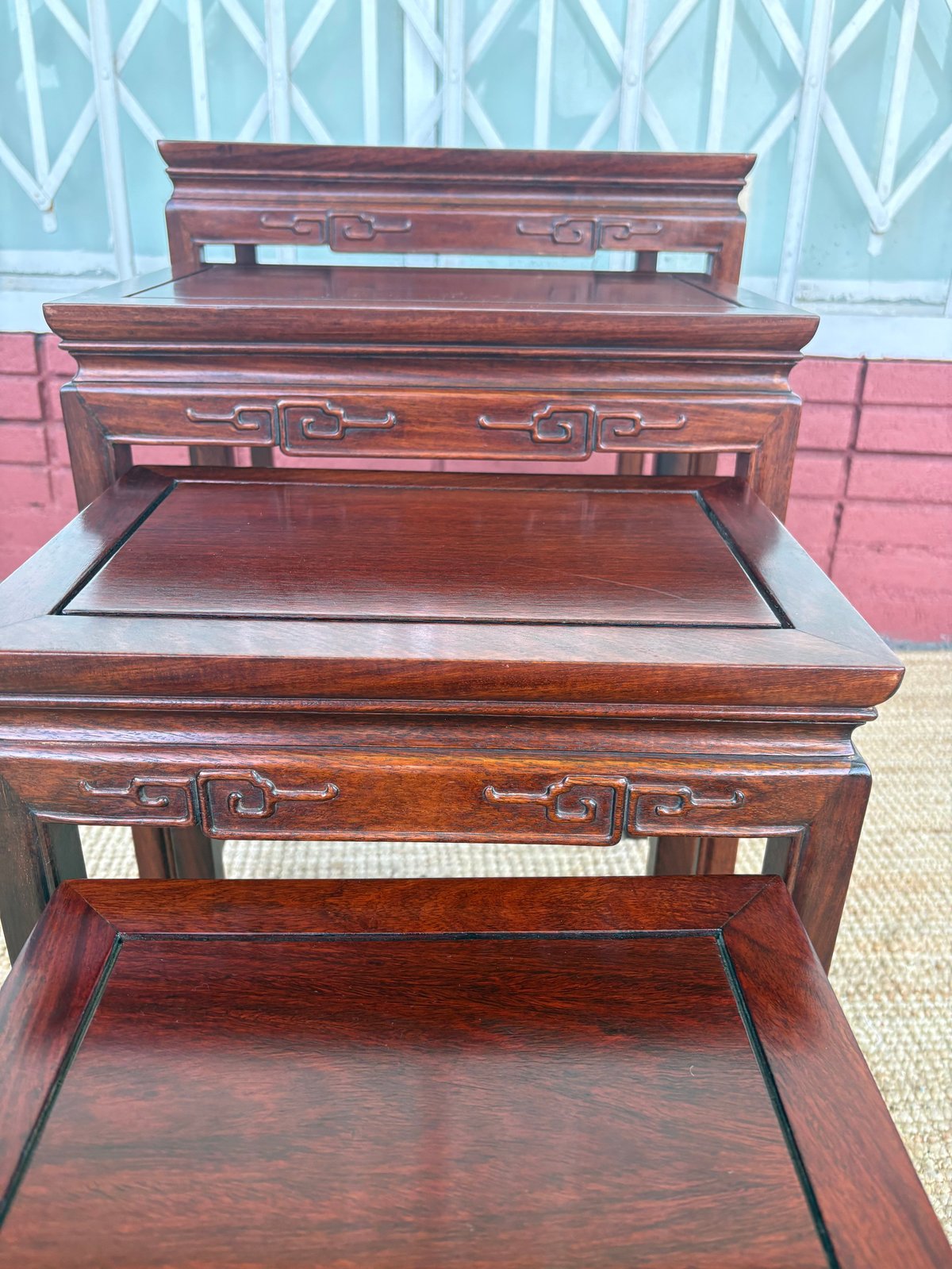 Stacked wooden furniture pieces with ornate metal handles and carved details displaying an open storage surface