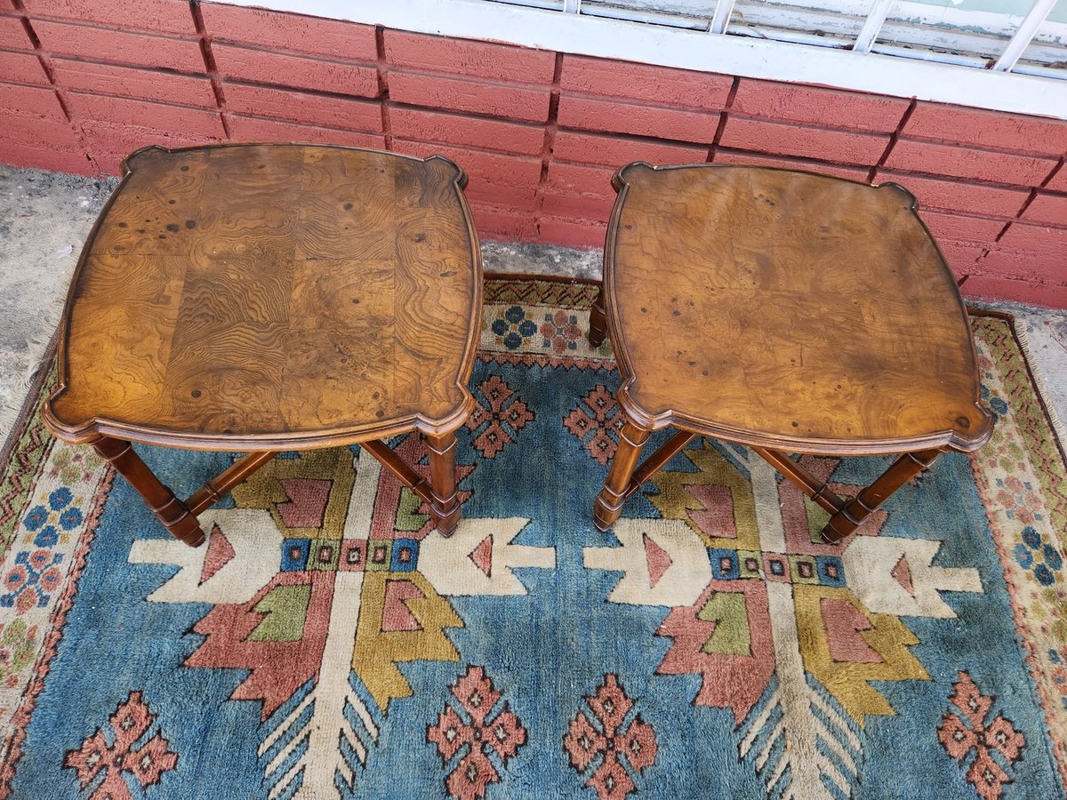 Two tan leather footstools with wooden legs positioned on a colorful patterned blue rug with geometric designs
