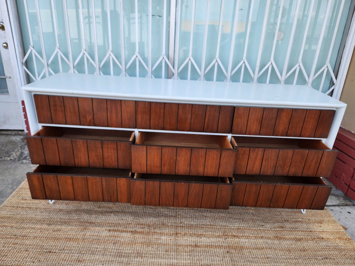 Wooden dresser with white top frame and three rows of wood-fronted drawers on garage floor