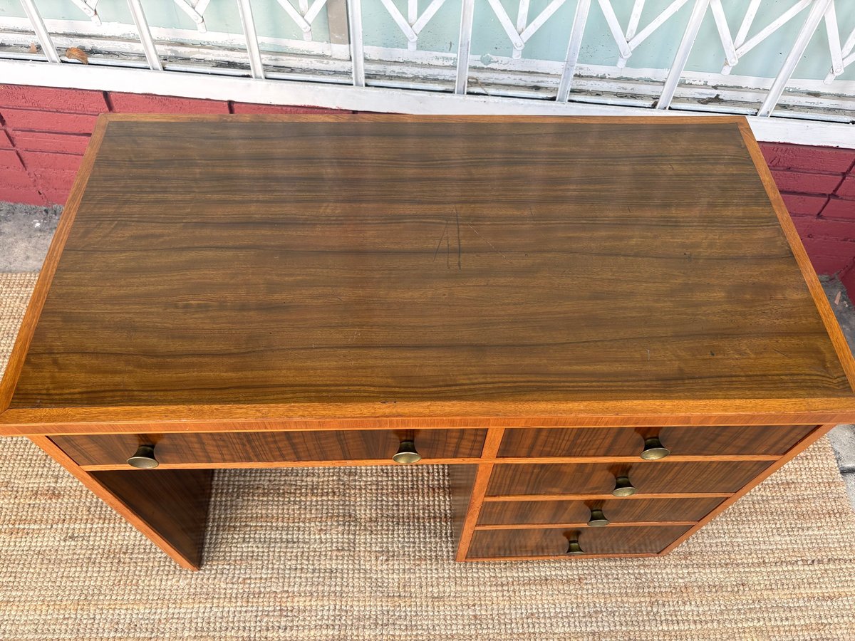 Wooden desk with multiple drawers and open shelving compartments on a beige rug