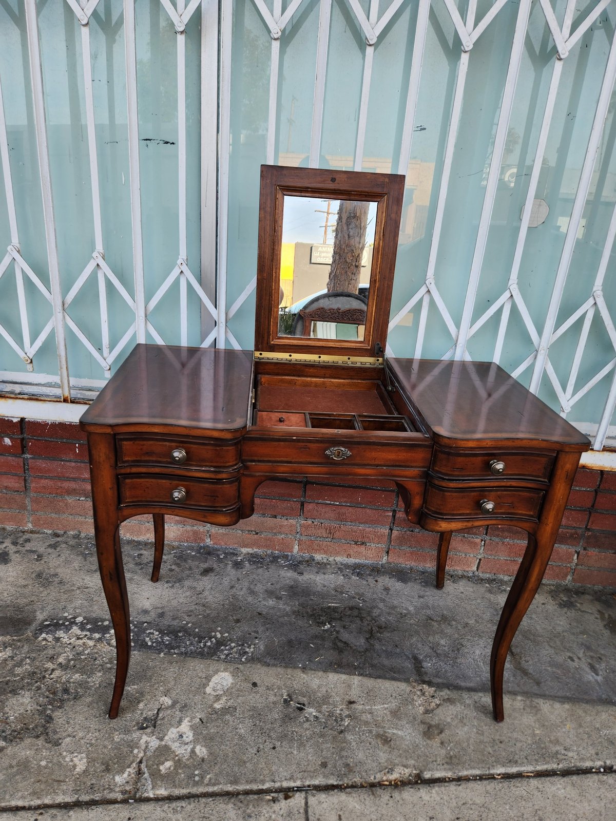 Vintage wooden vanity desk with mirror and drawers against a mint green and white patterned backdrop