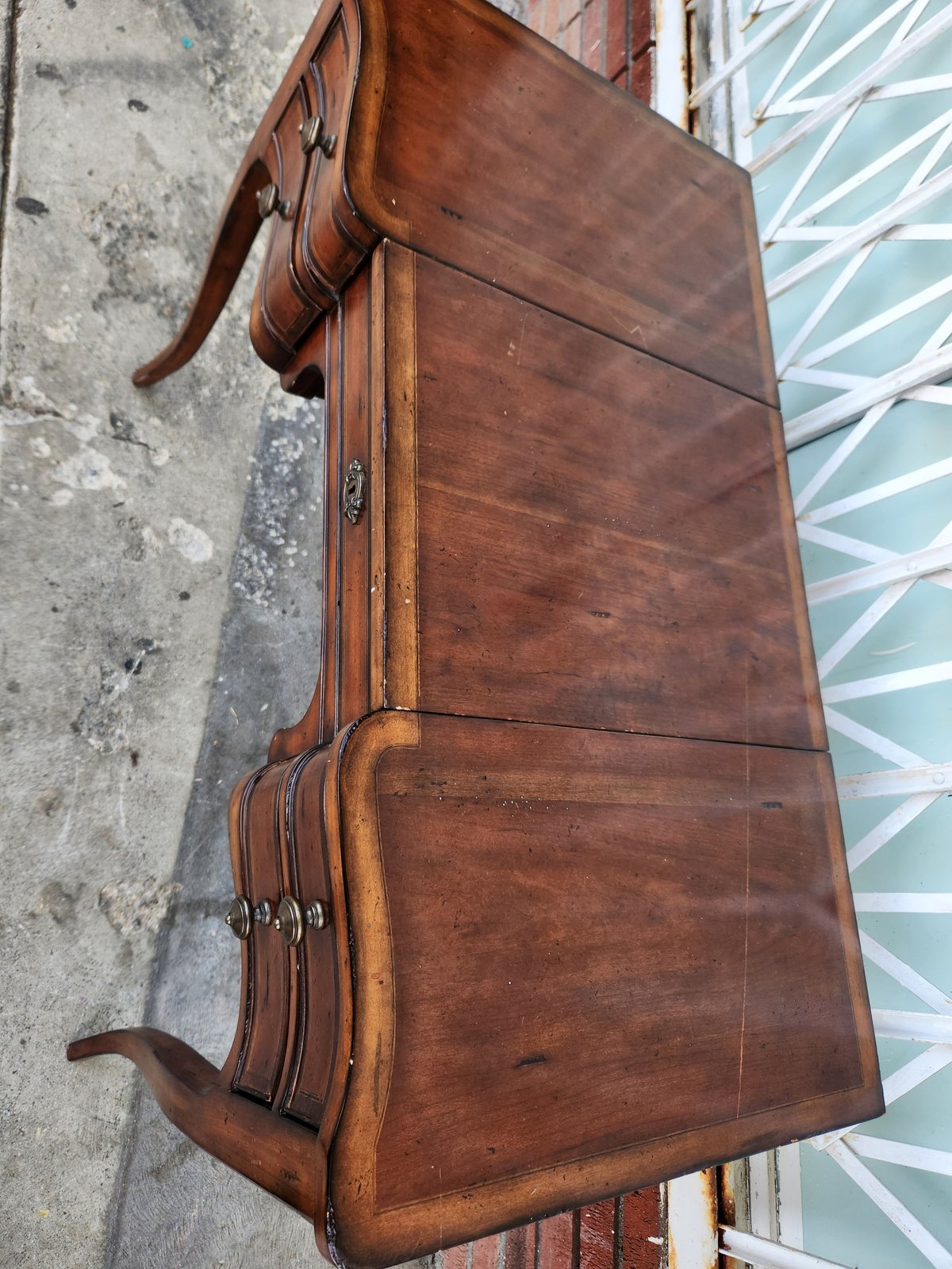 Vintage brown leather suitcase with handles and metal clasps on concrete ground next to blue and white door