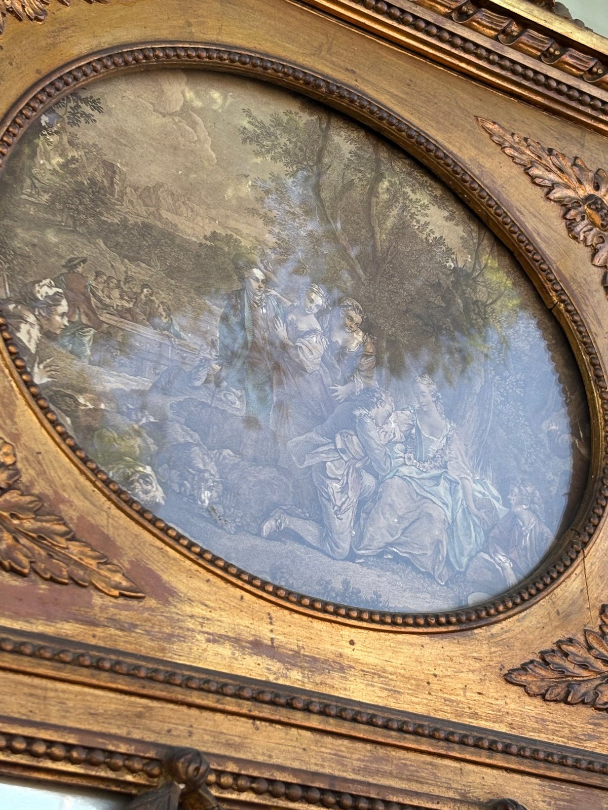 Oval framed classical artwork mounted in ornate wooden panel with decorative carved details