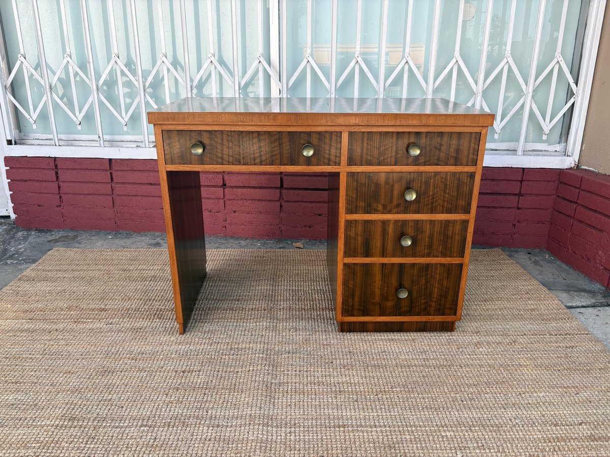 Vintage wooden desk with drawers on tan carpet against white and red wall backdrop