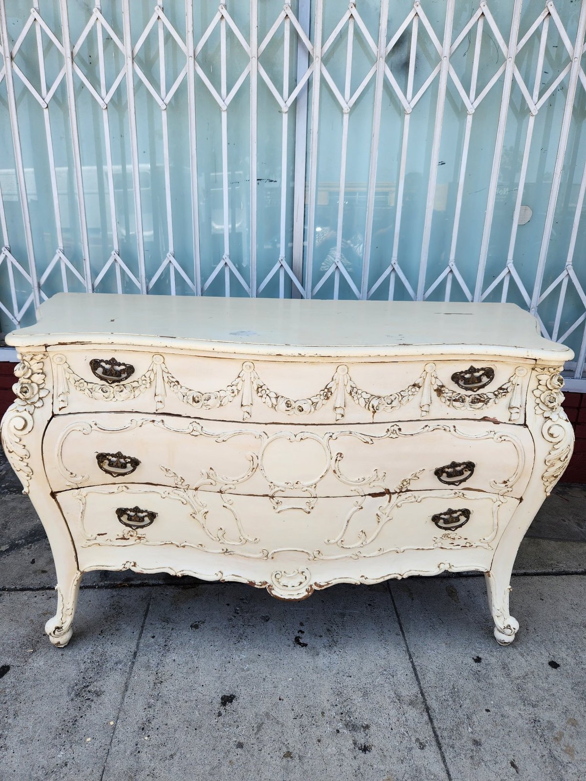 Antique white baroque dresser with ornate carved details and decorative handles displayed outdoors