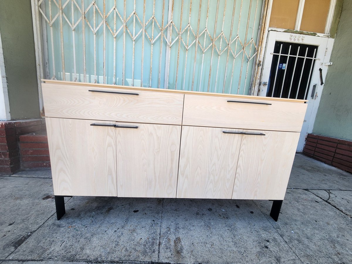 Light wood kitchen cabinet with four lower cabinet doors and two top drawers, displayed outdoors on pavement