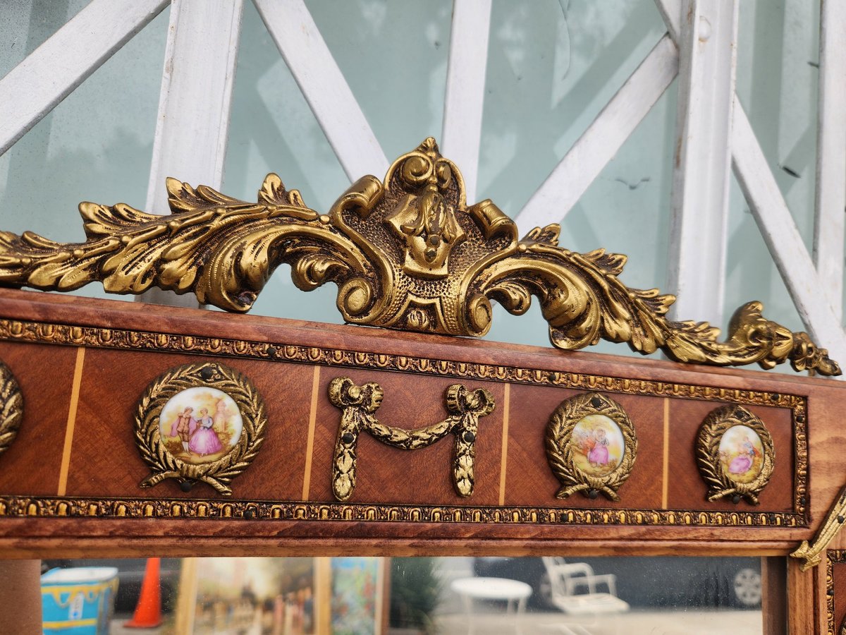 Ornate wooden mirror frame with gold carved details and decorative porcelain medallions