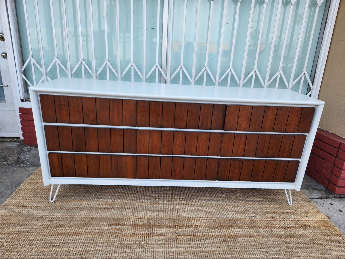 Mid-century modern crib with white frame and brown wood paneling on textured outdoor mat