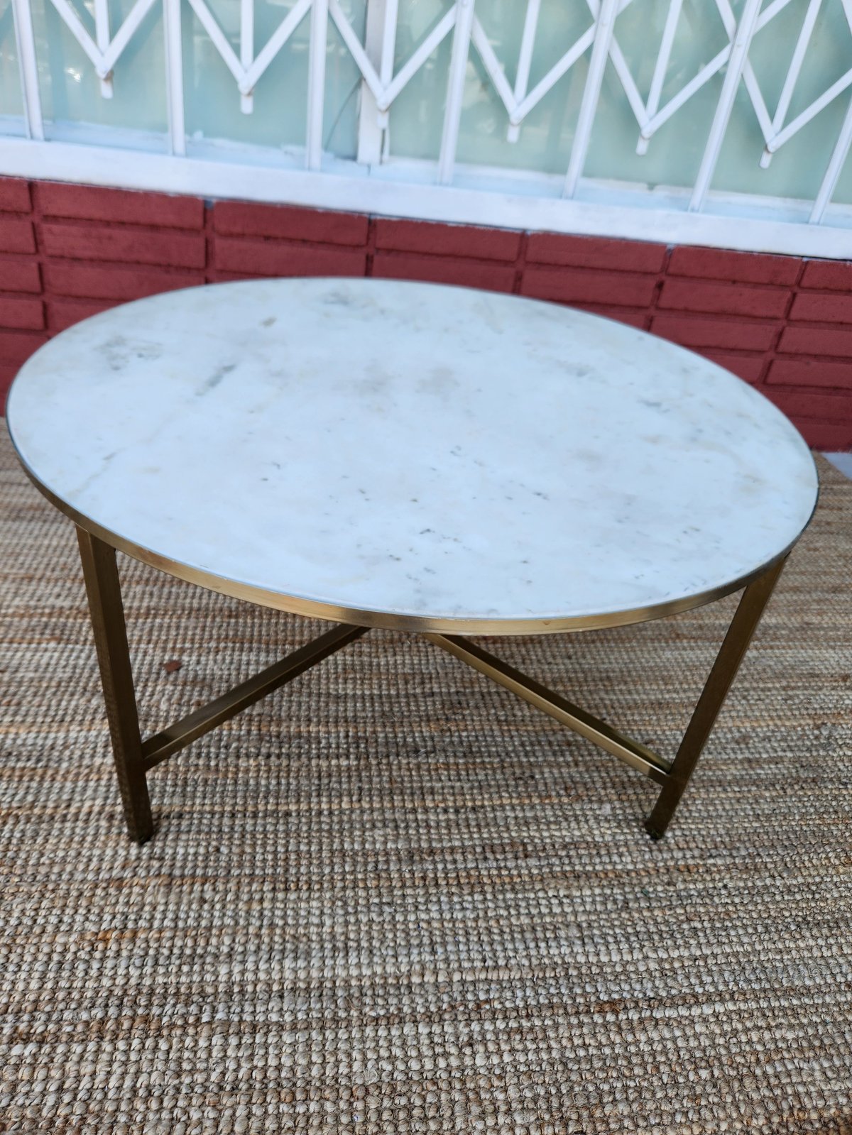 Oval marble-top coffee table with brass base on outdoor patio area