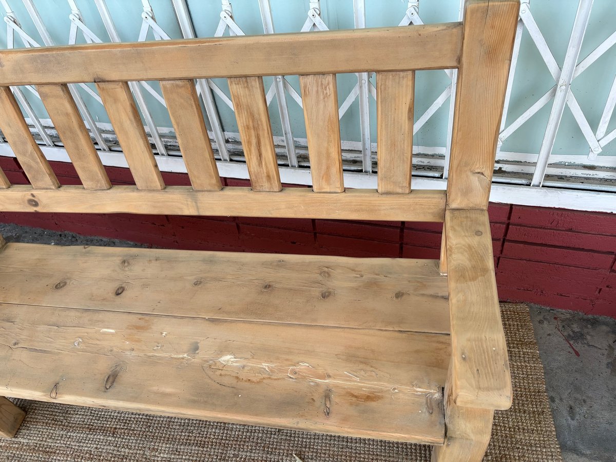 Wooden bed frame with light wood headboard and footboard, burgundy base rail, and metal grille window in background