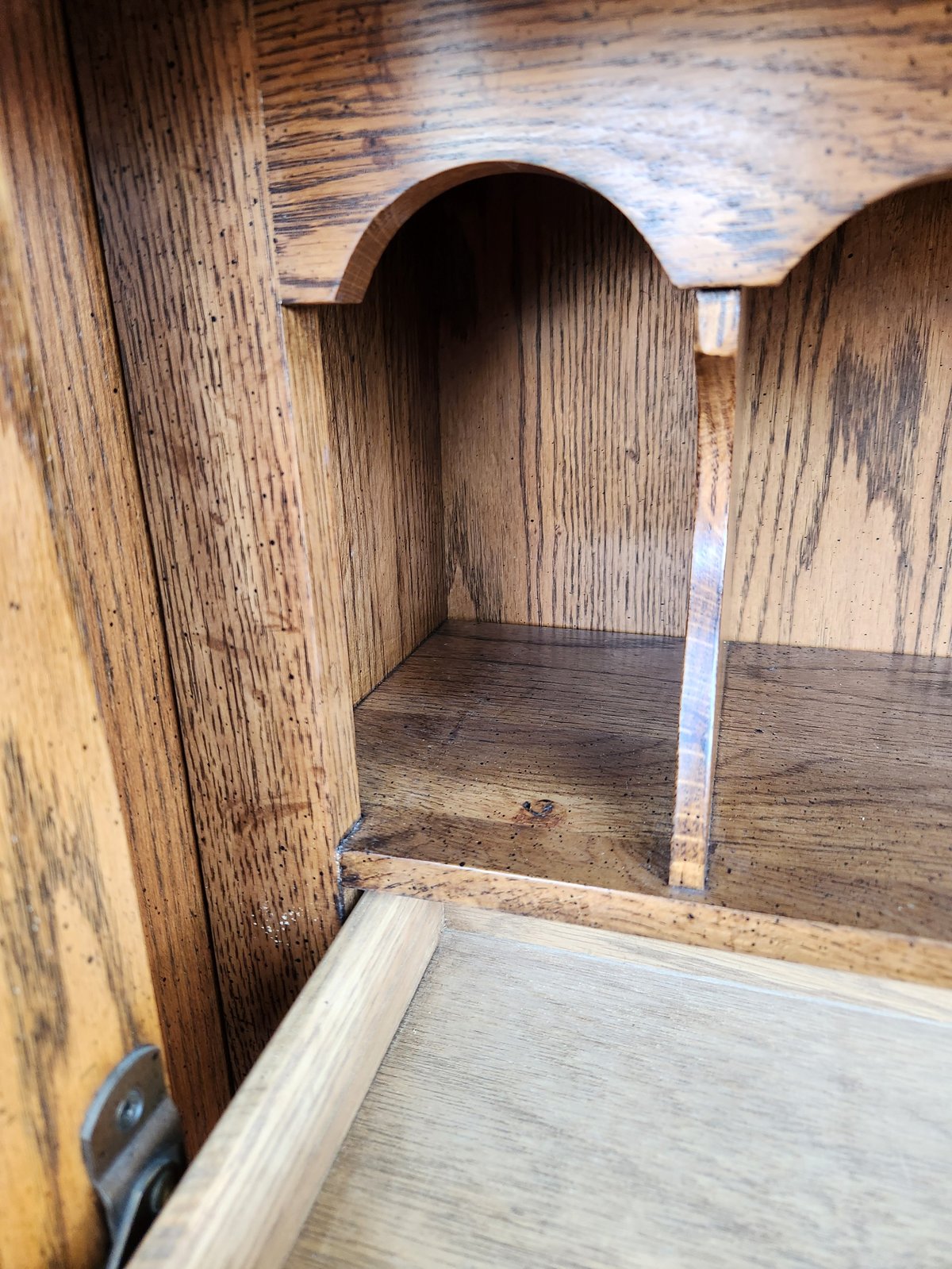 Interior of wooden cabinet or hutch with arched doorway opening, showing wooden shelving and rustic weathered finish