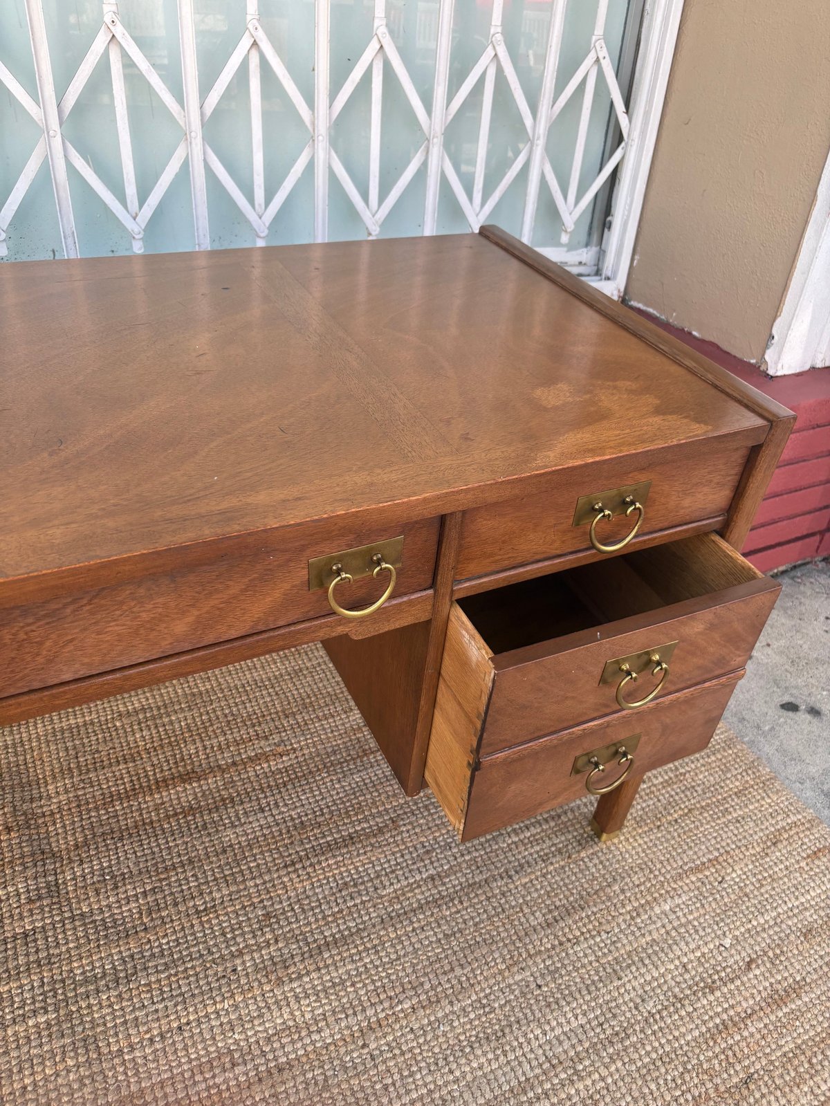 Wooden desk with brass handles and open drawer, displaying warm brown finish and traditional style