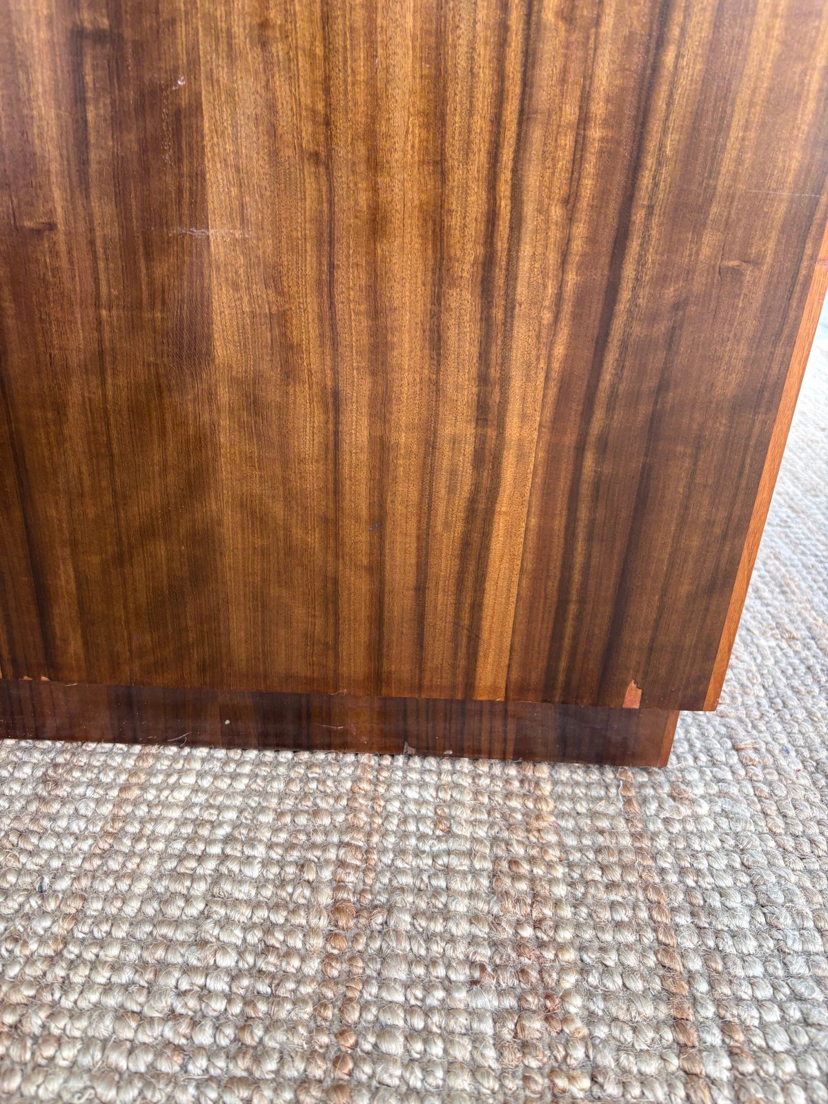 Close-up of a wooden panel with vertical grain texture on gray carpet flooring