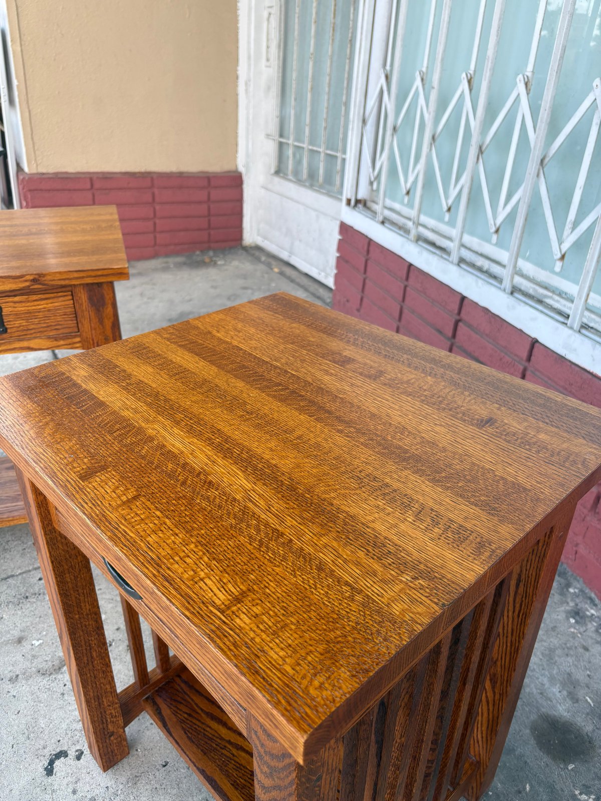 Wooden furniture on a covered patio with red brick walls and white metal gate door