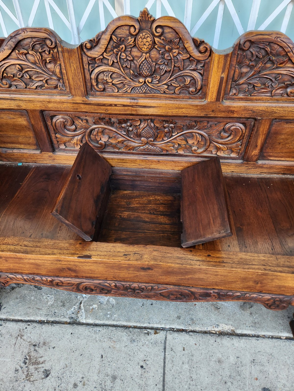 Antique wooden furniture piece with ornate carved decorative headboard and storage compartment