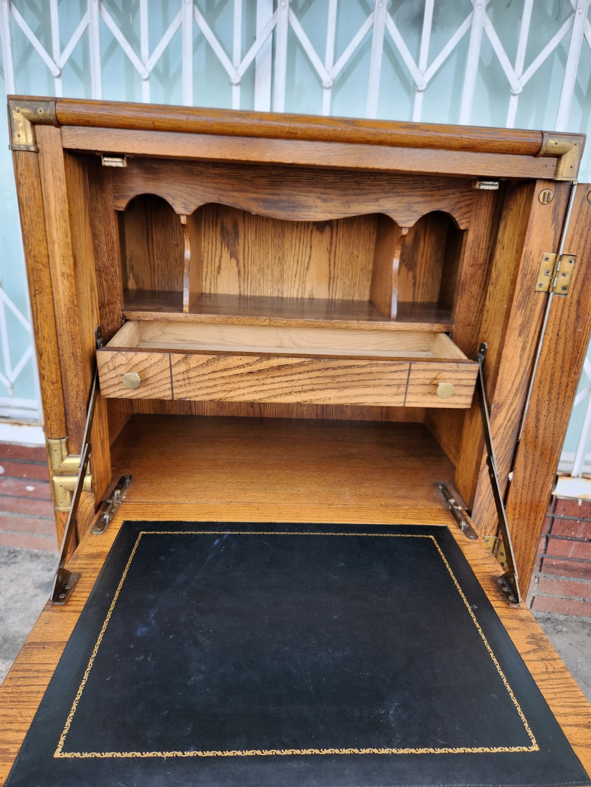 Open wooden secretary desk with drop-front panel, interior shelf, and black leather writing surface with gold trim