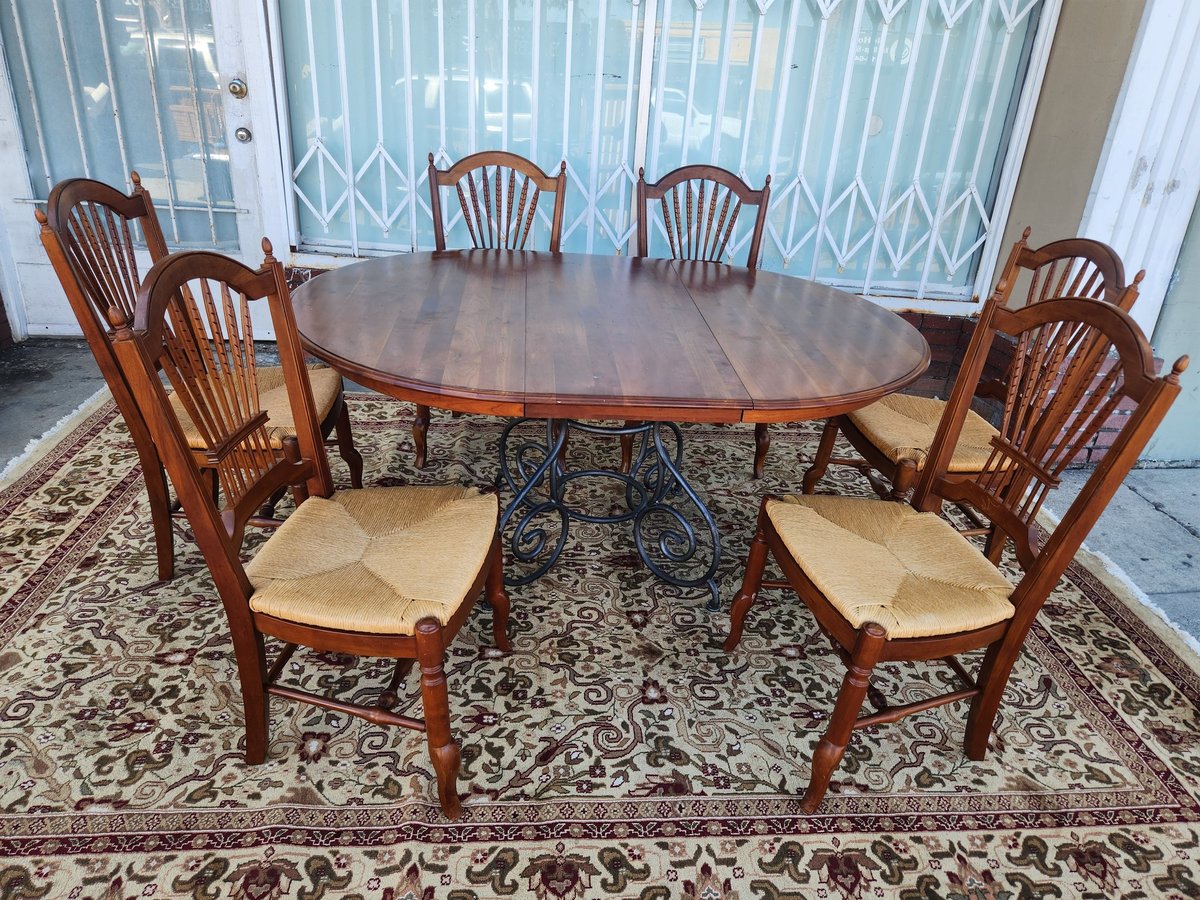 Wooden dining set with round table and six chairs with cream cushions on an ornate area rug