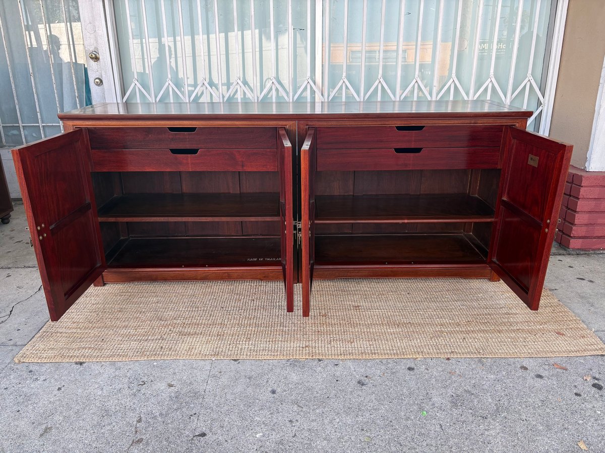 Red wooden storage cabinet with two open doors and shelves, displayed on concrete ground outdoors