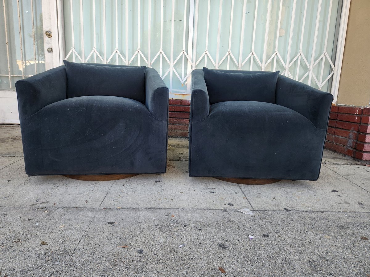 Two dark blue curved armchairs positioned side by side on a concrete surface outdoors
