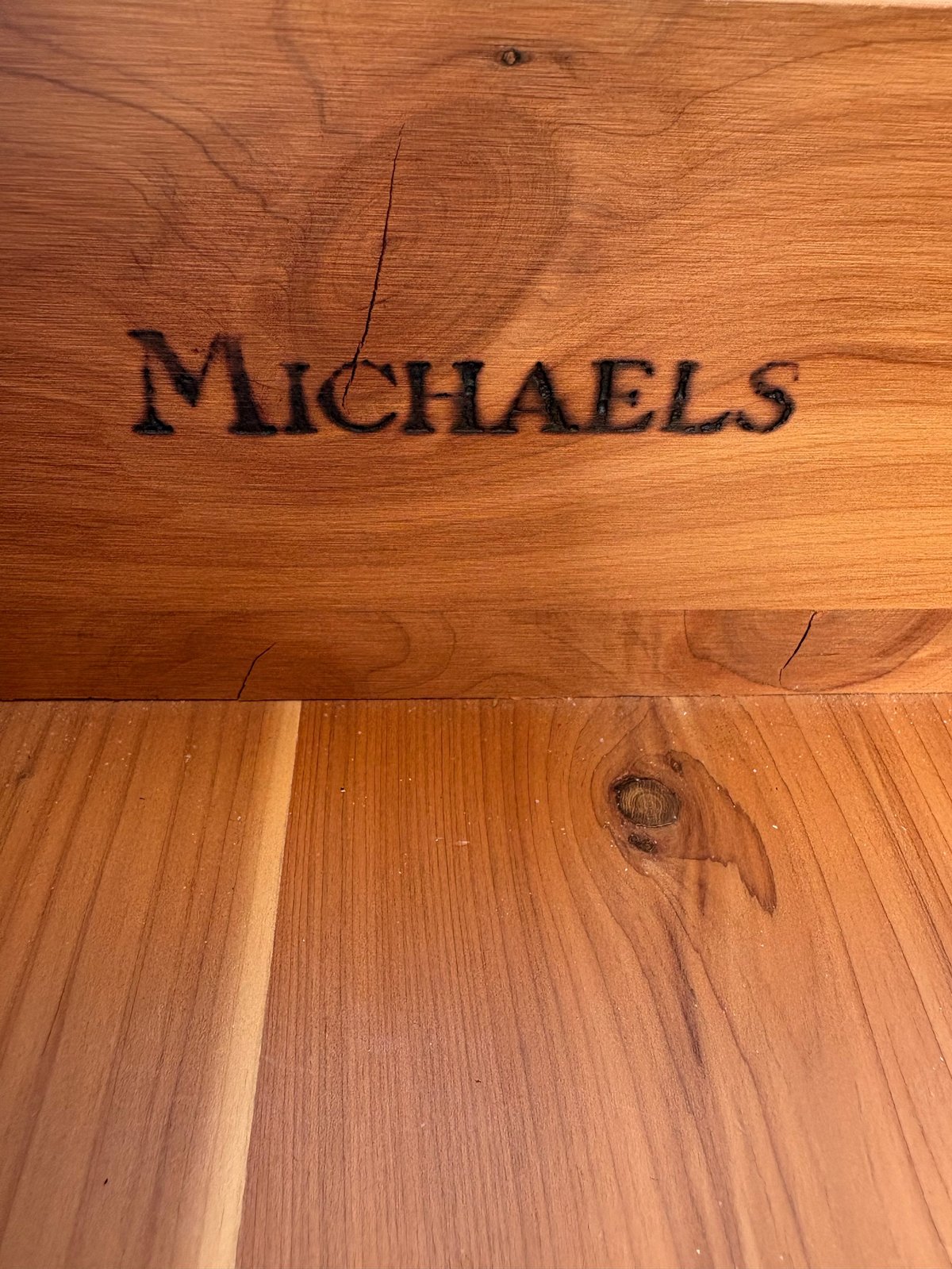 Michaels text engraved on natural wood surface with visible wood grain and knots