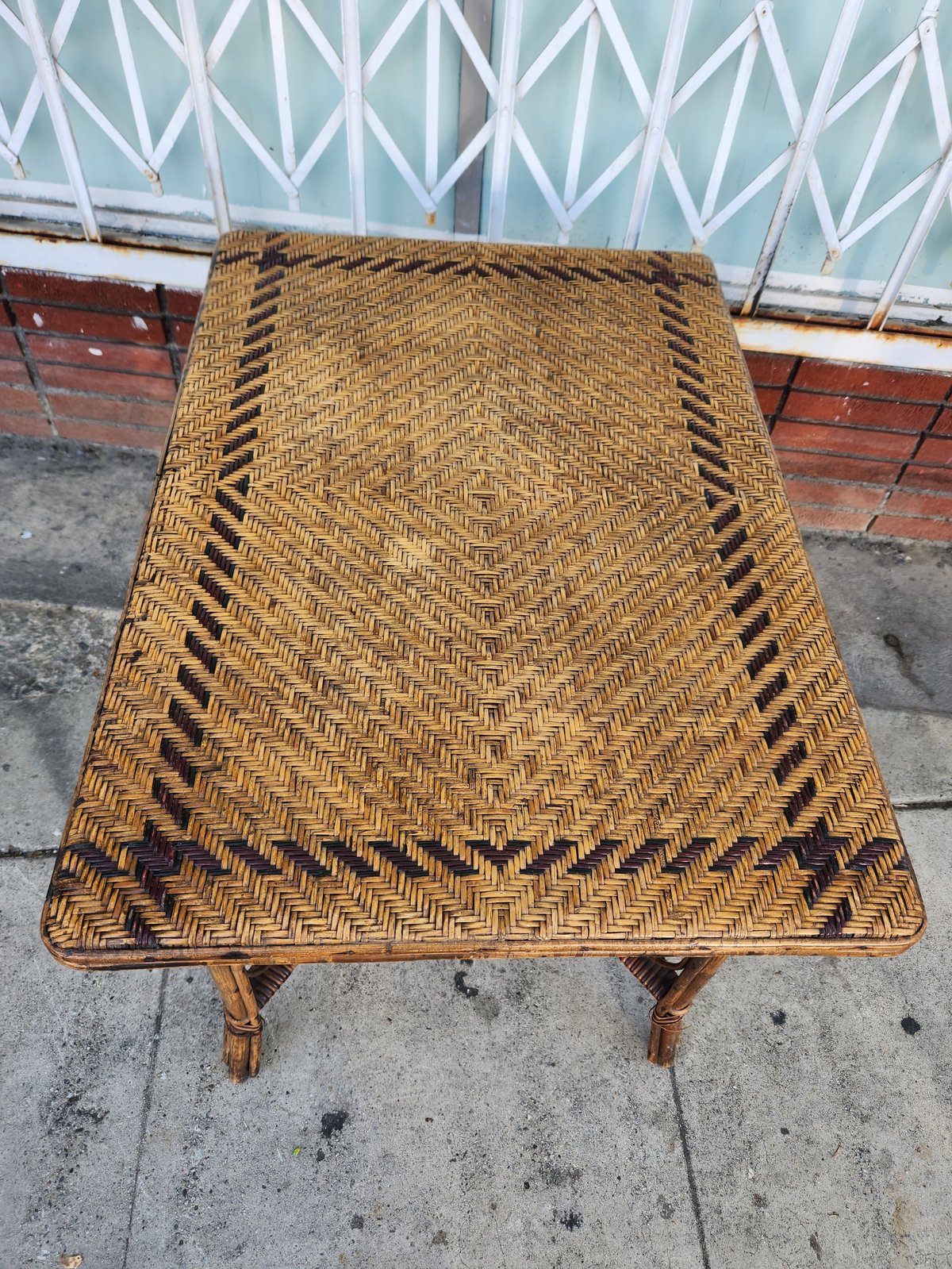 Woven wicker top rectangular table with bamboo legs on concrete patio