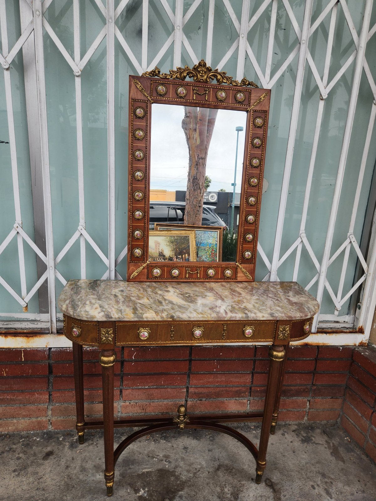 Antique wooden console table with marble top and ornate mirror with inlaid details against green and white patterned wall
