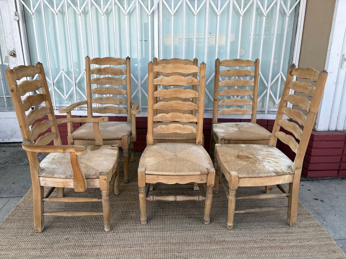 Set of six wooden ladder-back chairs with woven rush seats arranged in a room with teal blinds