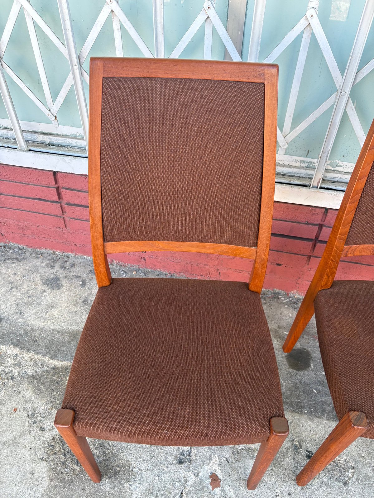 Wooden dining chair with brown fabric upholstery, featuring an orange-toned wooden frame and back support
