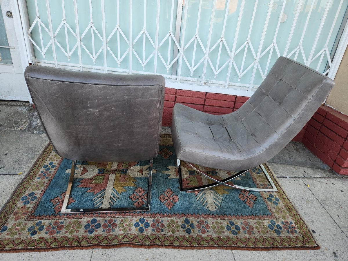 Two gray upholstered chairs on a blue and red patterned area rug in a room with white accordion doors and red wall paneling