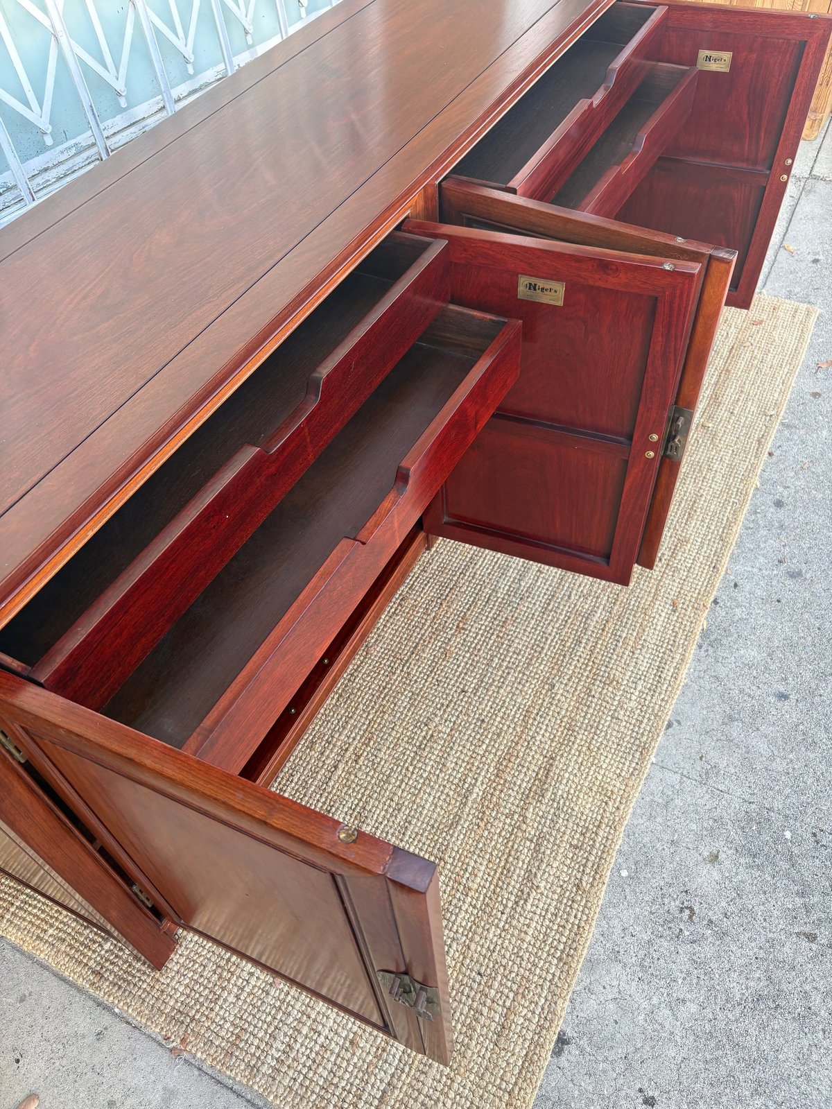 Wooden dresser with open drawers showing red interior and black drawer liners on a beige mat