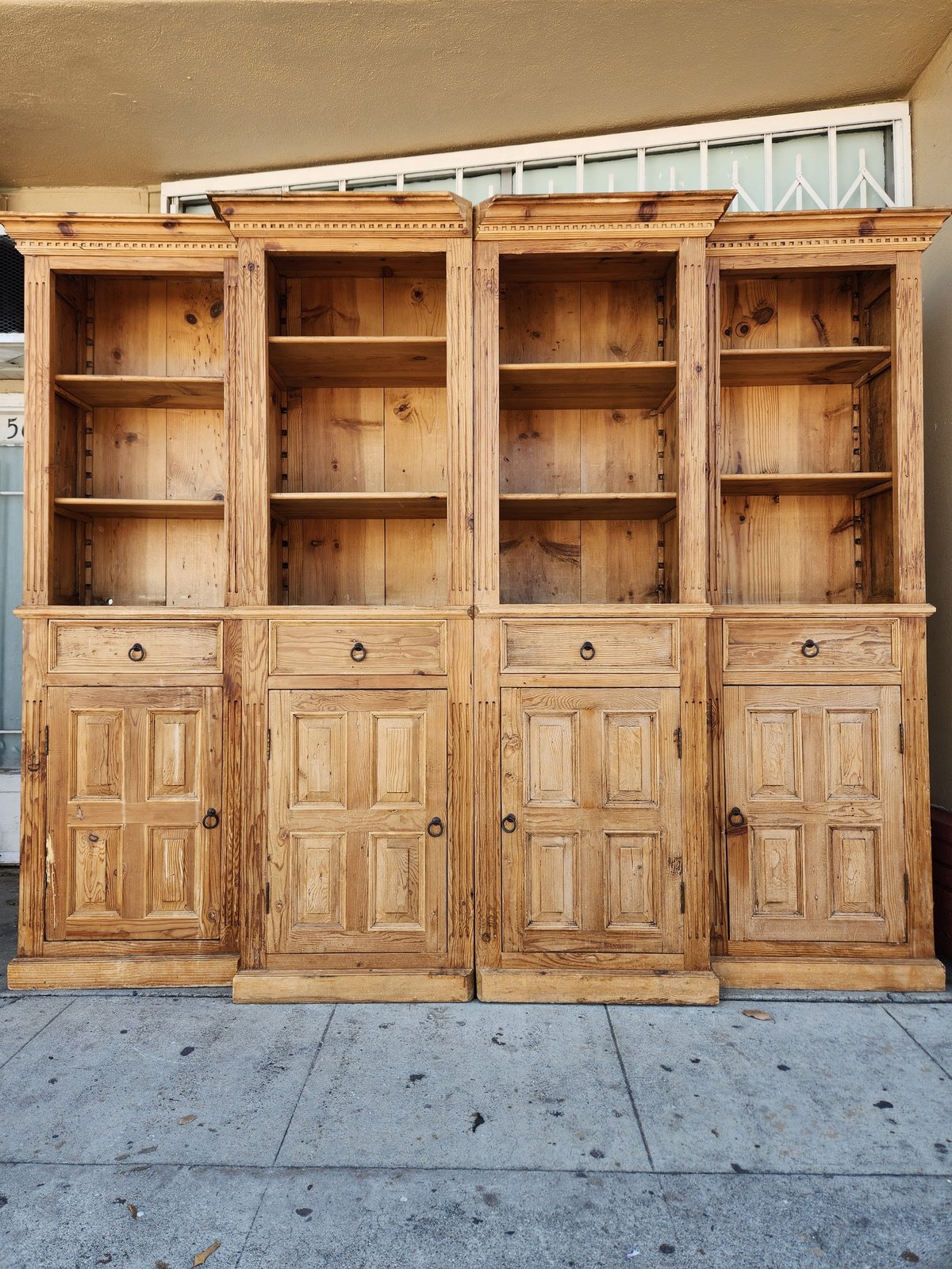 Large wooden cabinet with four glass-door display sections on top and four wooden cabinet doors with shelving below