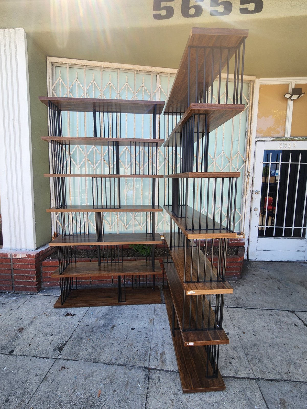 Multi-level wooden pet cage with metal bars and stairs on concrete patio outside a building