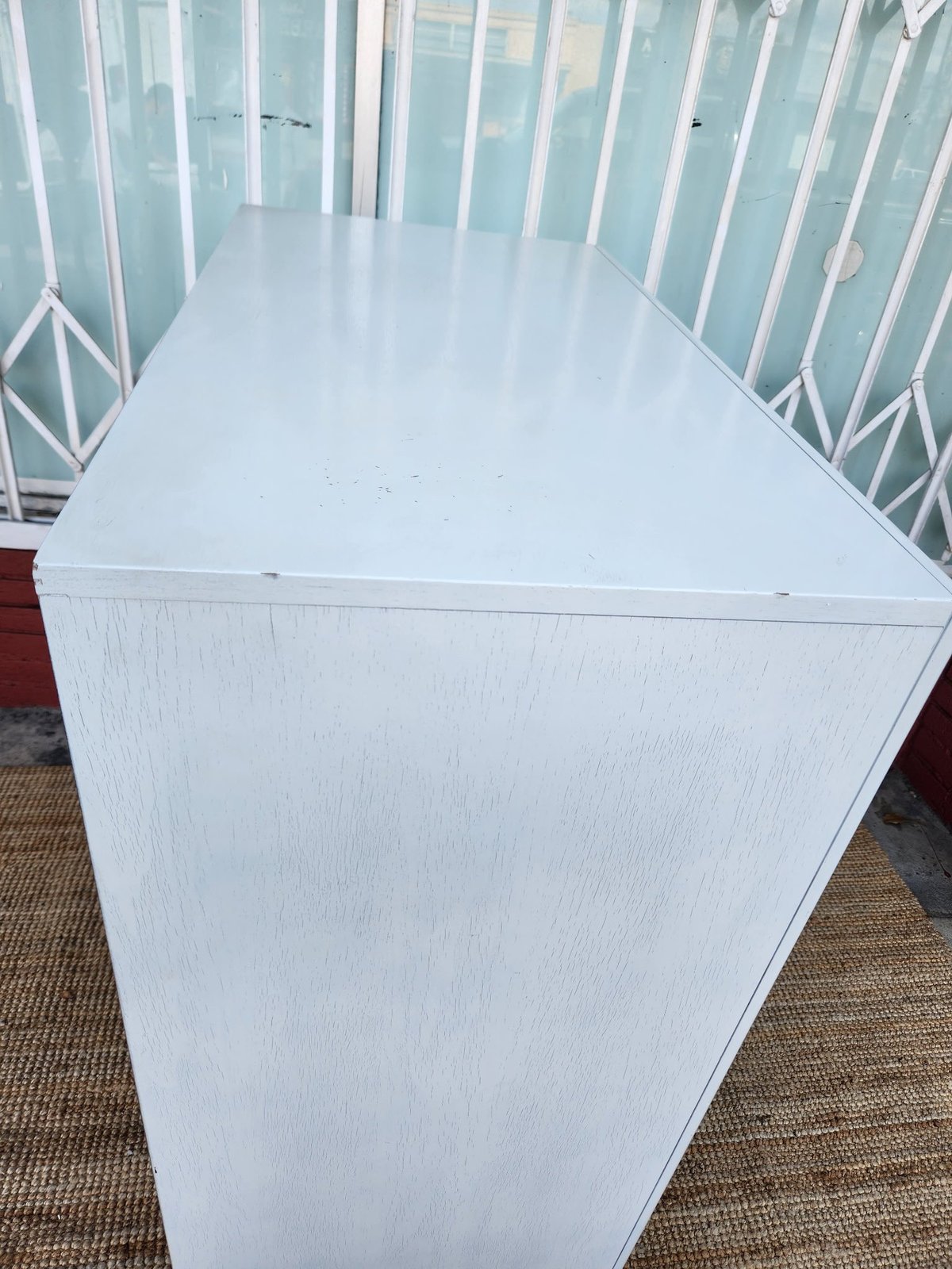 White rectangular table on brown carpet with white metal railing visible in background