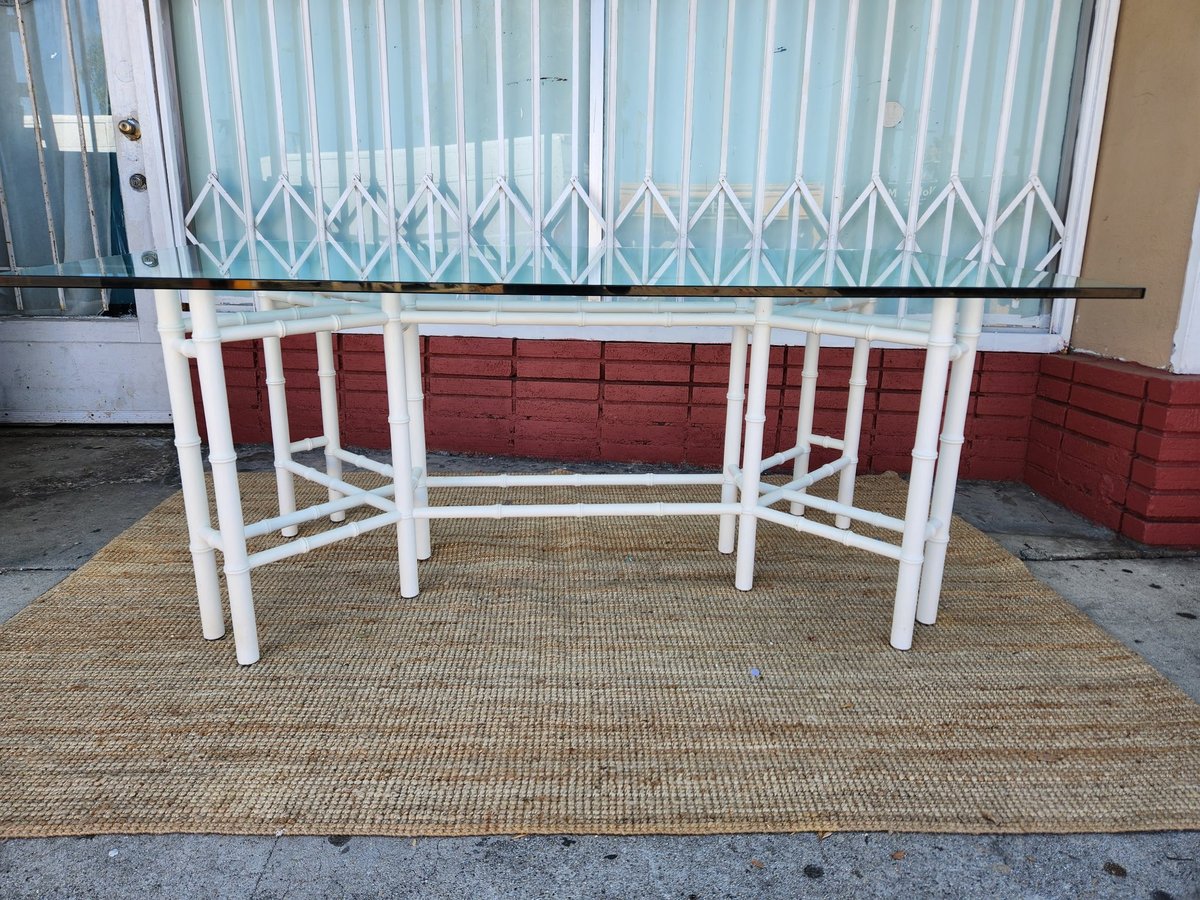 White metal frame table with glass top on tan rug against red brick wall and blue corrugated metal shutter