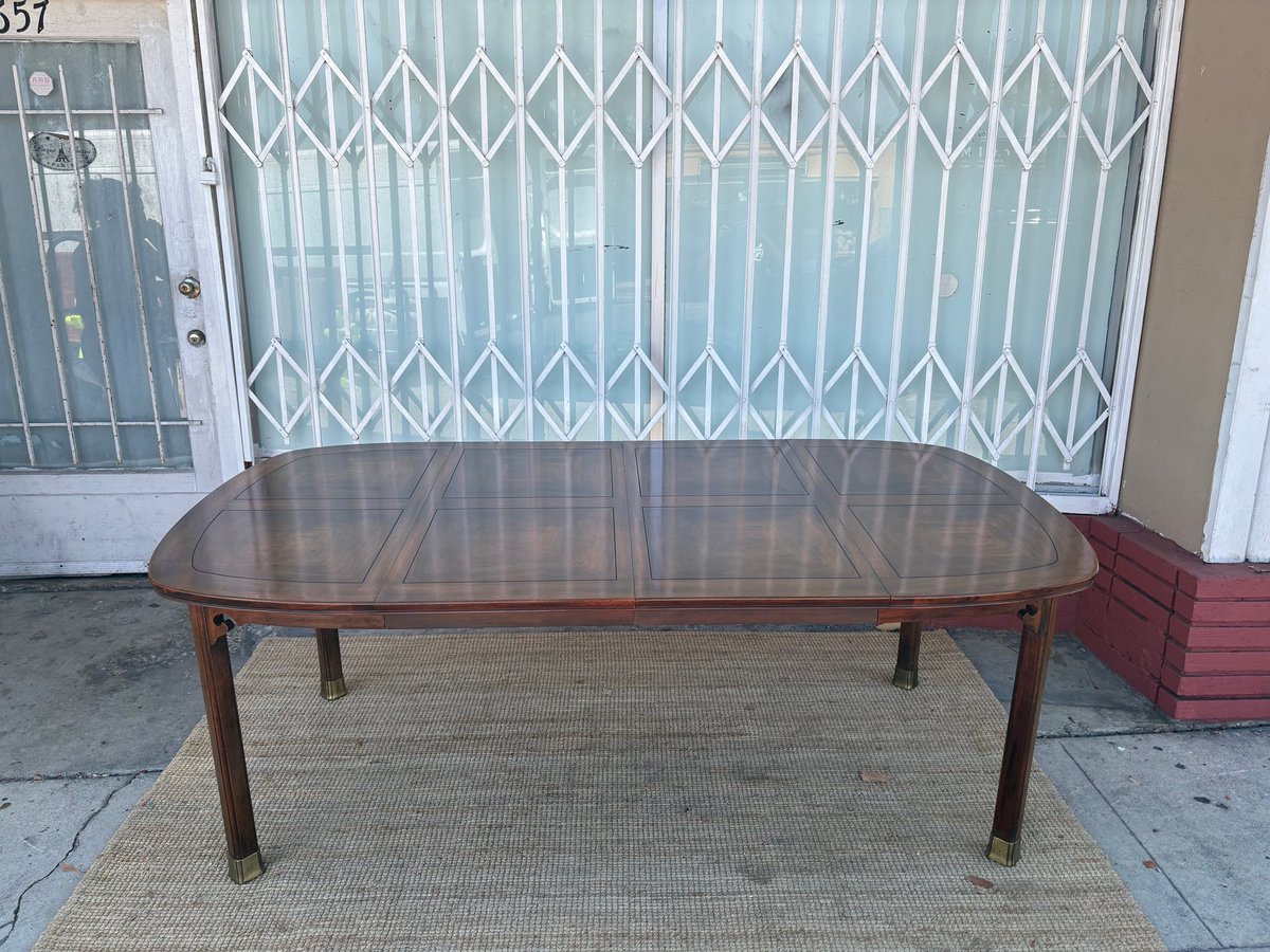 Brown wooden dining table on a beige rug in front of a metal security gate and white door