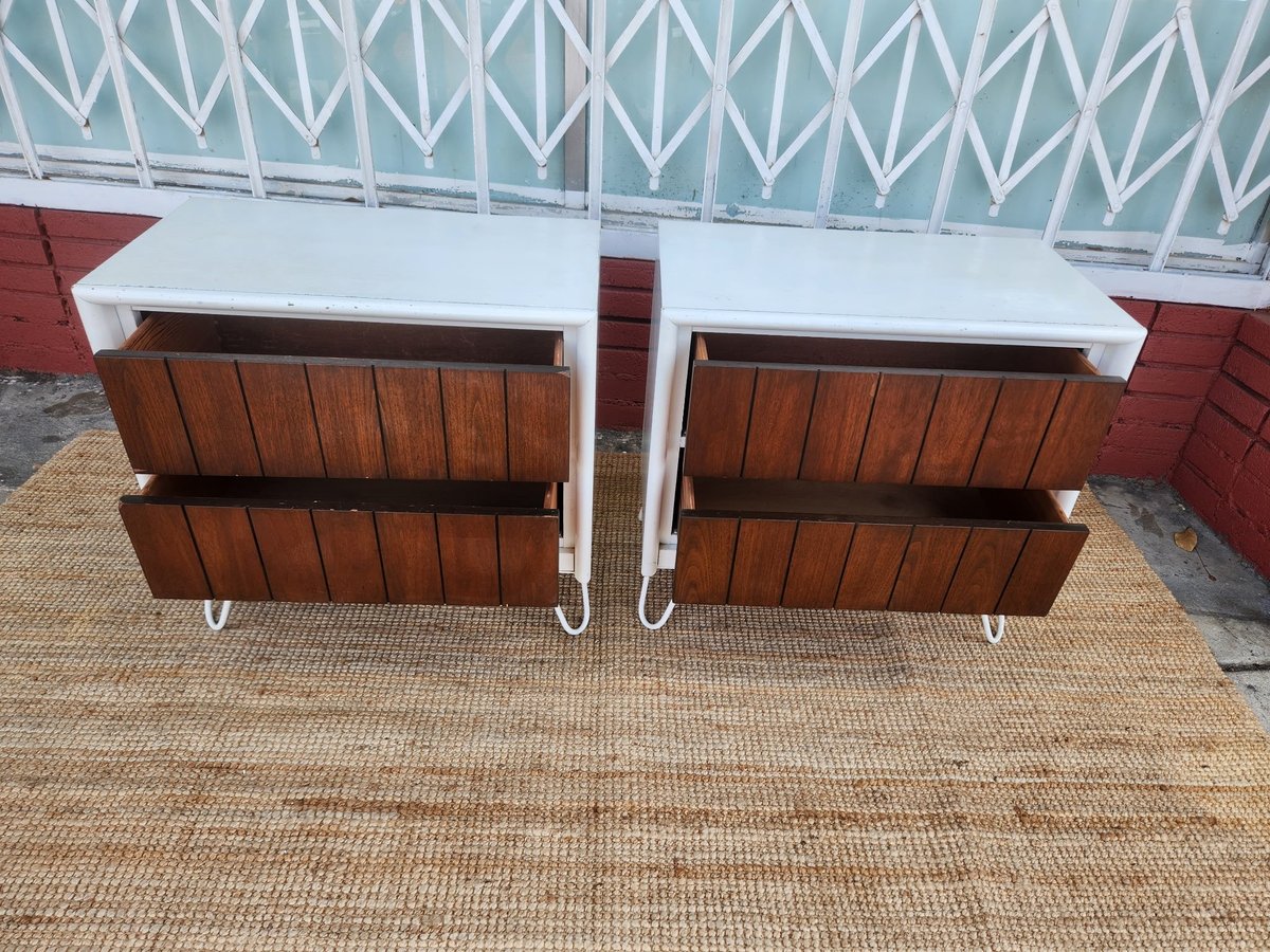 Two wooden feed troughs with white frames on a tan rubber mat inside a horse stable with teal diamond patterned roof.